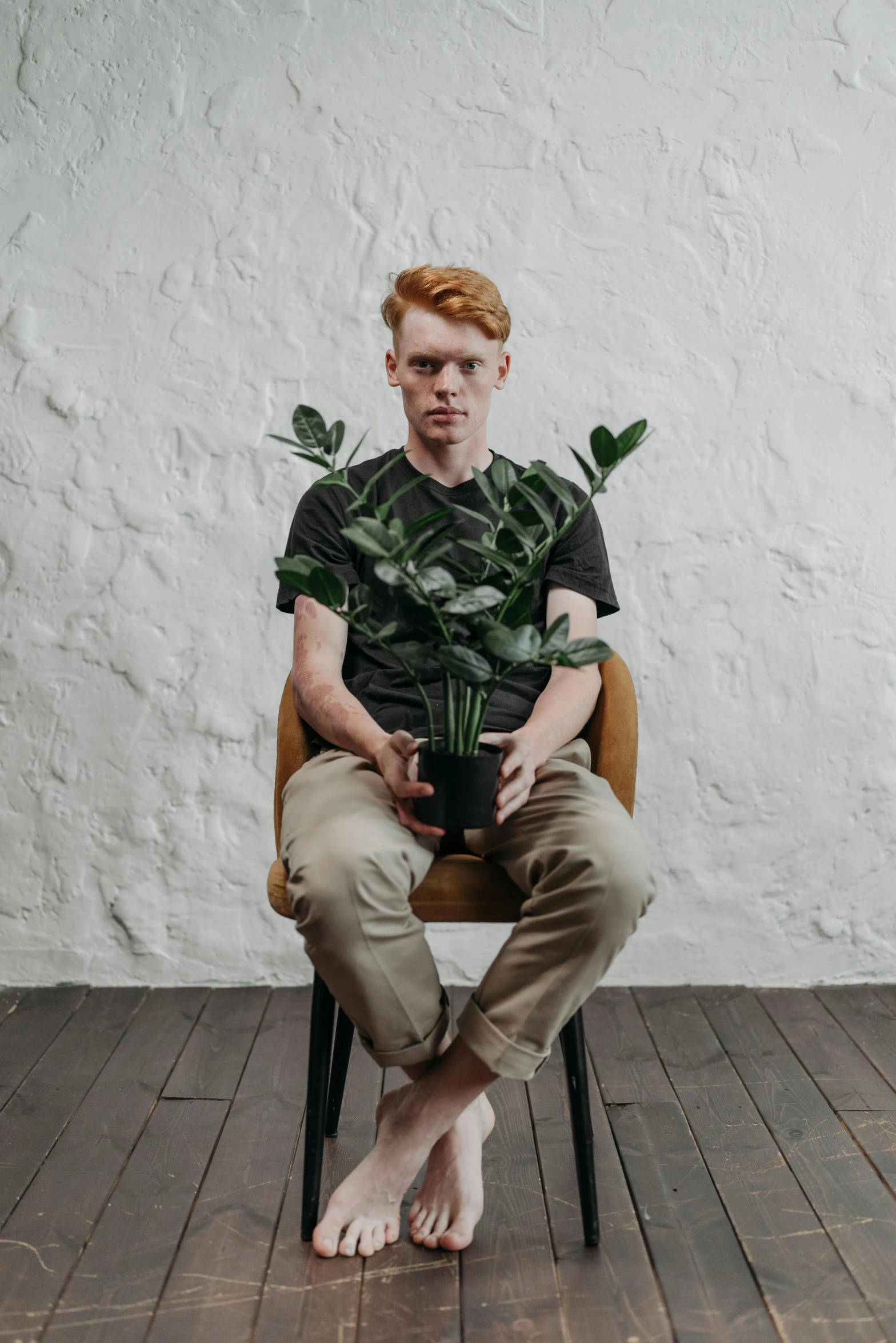 a man sitting in a chair holding a potted plant, inspired by Seb McKinnon, trending on unsplash, ginger hair, press shot, standing straight, thin young male