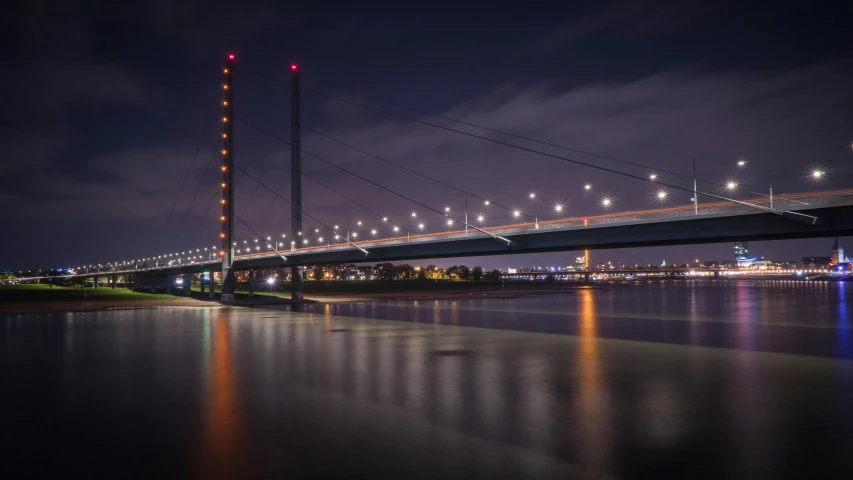 a bridge over a body of water at night, by Eglon van der Neer, pexels contest winner, fan favorite, panoramic shot, portrait of tall, floating power cables