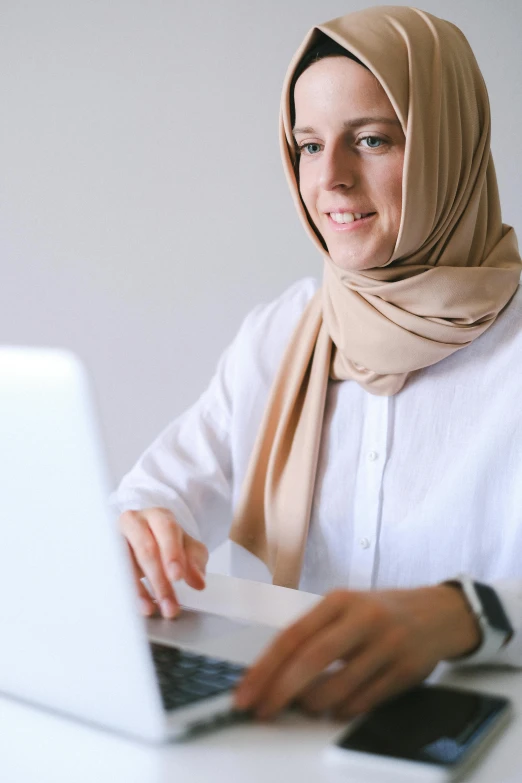 a woman sitting in front of a laptop computer, hurufiyya, thumbnail, white scarf, language, precision