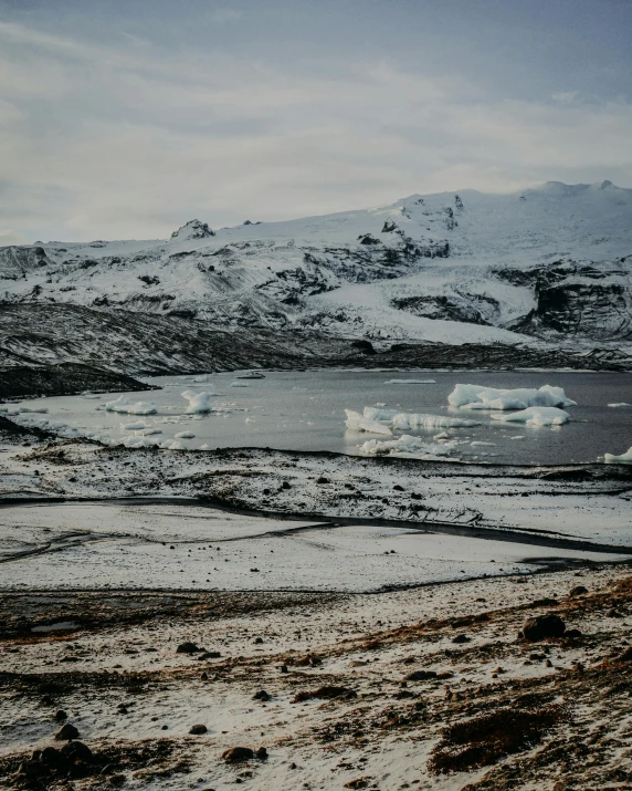 a body of water surrounded by snow covered mountains, documentary photo, iceland photography, ground covered with snow