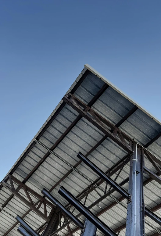 a metal structure with a blue sky in the background, a portrait, by Carey Morris, unsplash, galvalume metal roofing, large overhangs, close - up profile, square