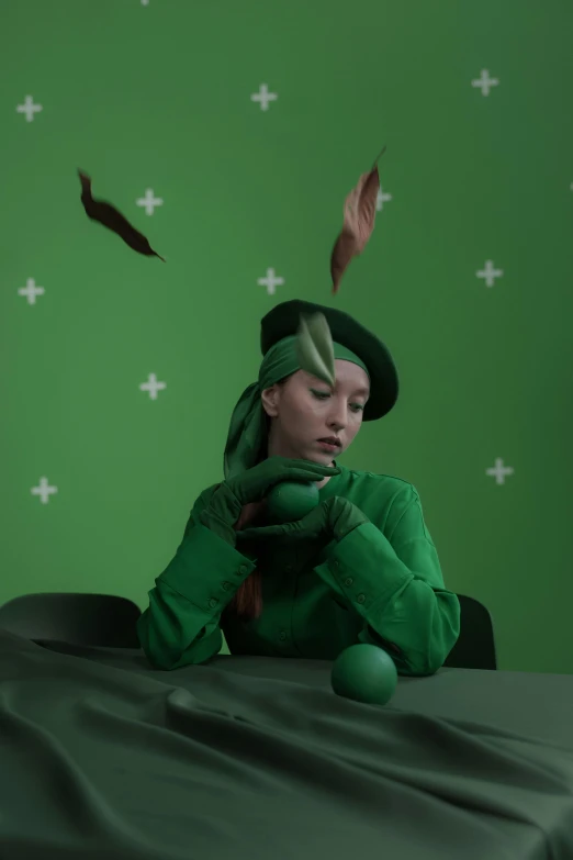 a woman sitting at a table in front of a green screen, inspired by Hans Baldung, trending on pexels, the madhatter, showstudio, feathers growing from arms, cai xukun