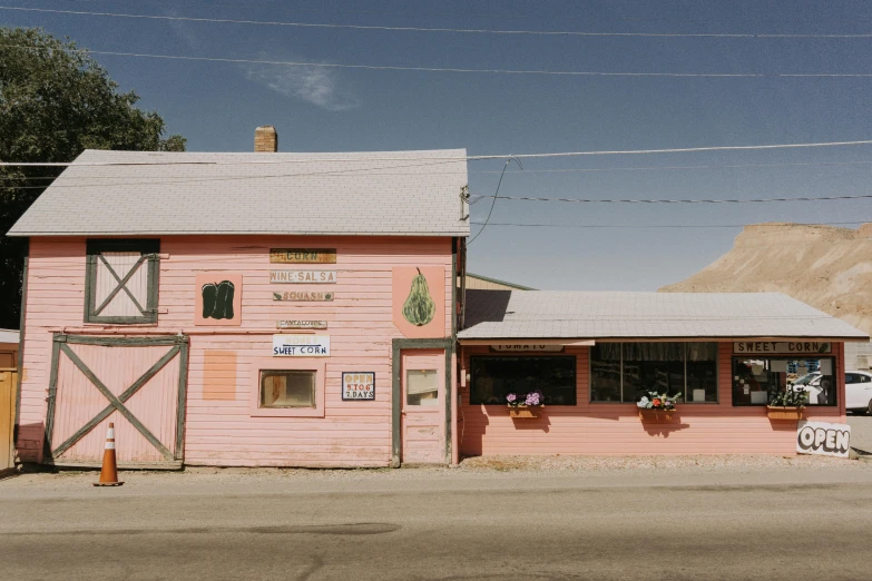 a pink building sitting on the side of a road, wind river valley, old shops, jen bartel, restaurant