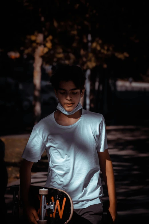 a young man holding a skateboard in the dark, pexels contest winner, happening, in white turtleneck shirt, wearing facemask, walking boy, in the sun