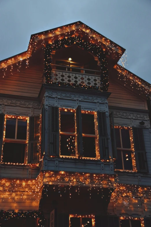 a house is lit up with christmas lights, a photo, pexels contest winner, art nouveau, ✨🕌🌙, peaceful wooden mansion, amber glow, low detail