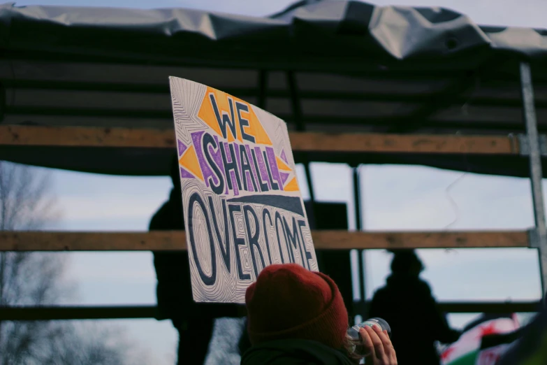 a person holding a sign at a protest, pexels, excessivism, sheild, inspire and overcome, instagram picture, covered in