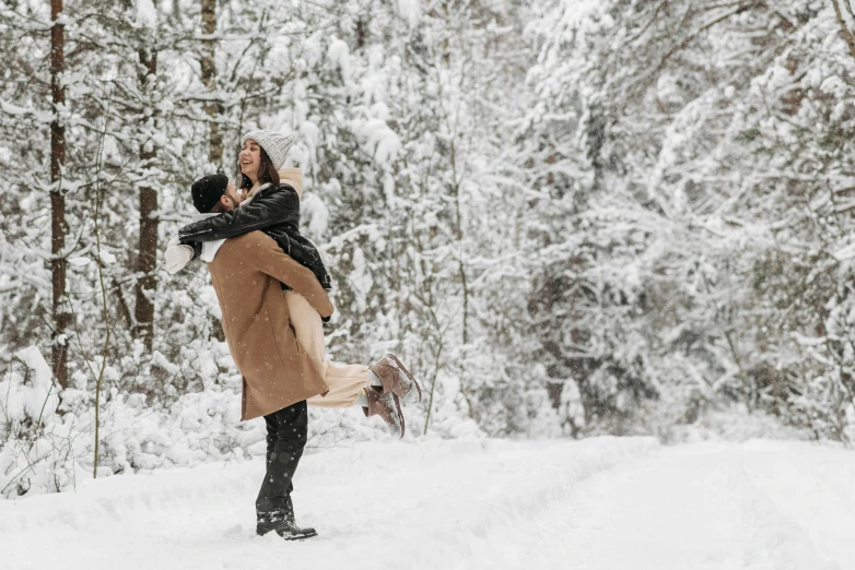 a man holding a woman in his arms in the snow, pexels contest winner, thumbnail, all overly excited, snow on trees and ground, tan