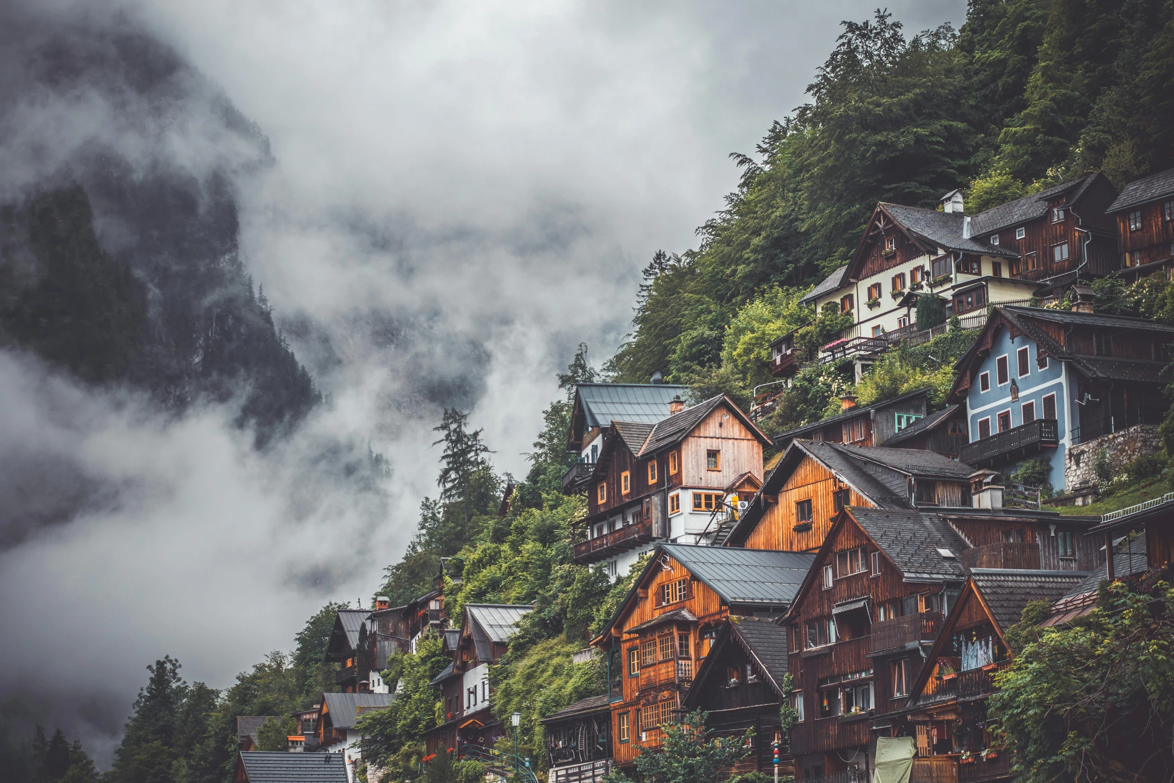 a group of houses sitting on top of a lush green hillside, by Sebastian Spreng, pexels contest winner, under a gray foggy sky, chalet, highly ornate, a wooden