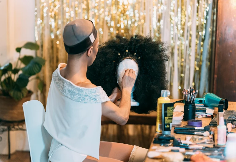 a woman that is sitting in front of a mirror, white man with black fabric mask, frosting on head and shoulders, sparkly, dry brushing