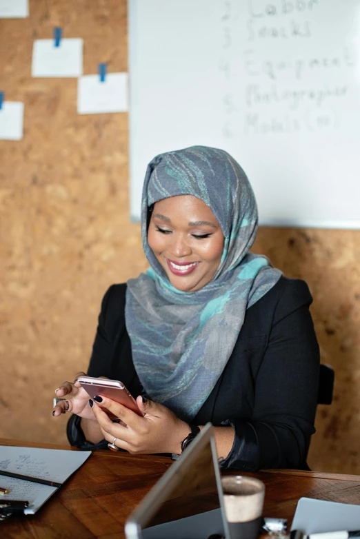 a woman sitting at a table using a cell phone, hurufiyya, teaching, high-quality photo, grey, riyahd cassiem