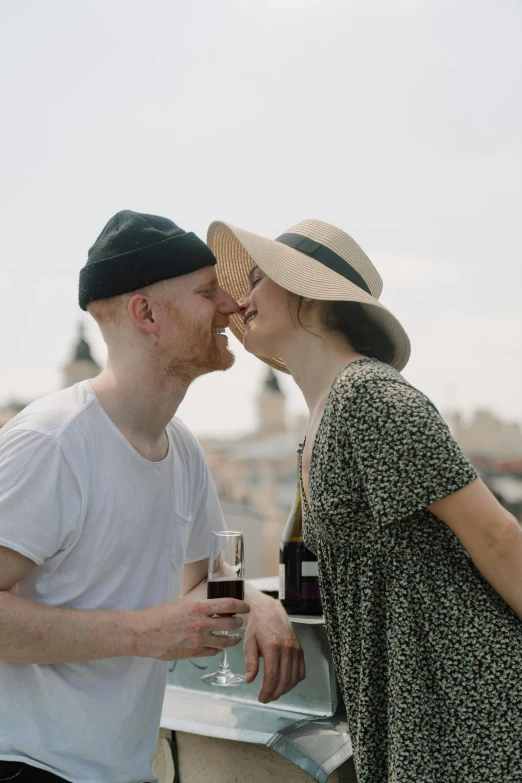 a man and a woman standing next to each other, pexels contest winner, drinking their hearts out, with hat, pale skin, on rooftop