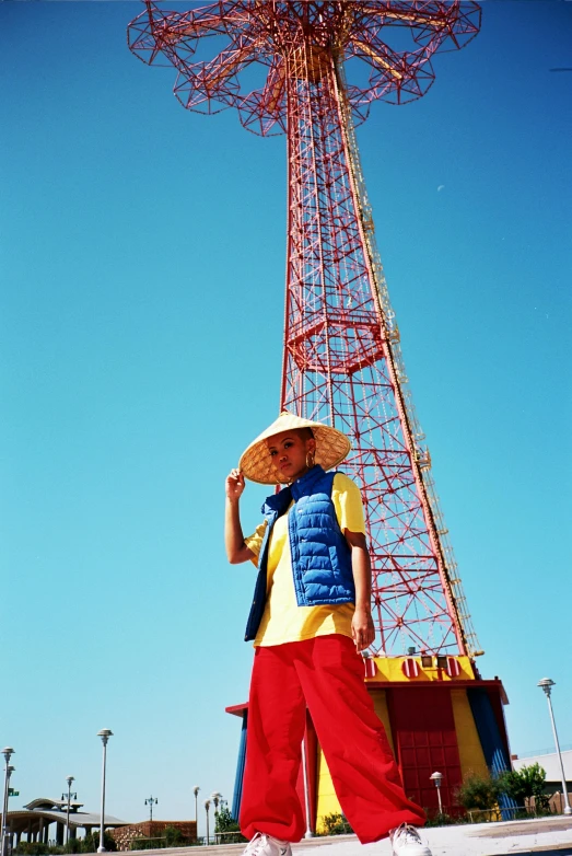 a man standing in front of a tall tower, inspired by Wes Anderson, unsplash, pop art, wearing a red backwards cap, in style of ren hang, digger land amusement park, los angeles 2 0 1 5