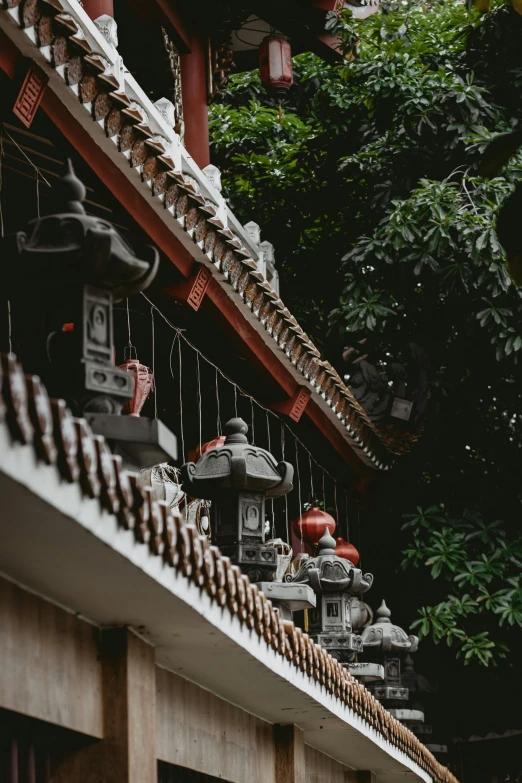 a row of lanterns hanging from the side of a building, a statue, inspired by Sesshū Tōyō, pexels contest winner, mingei, roof with vegetation, tlaquepaque, teapots, built into trees and stone