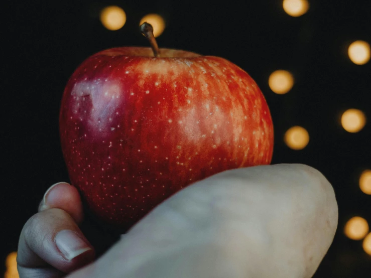 a close up of a person holding an apple, pexels contest winner, magic realism, background image, embrace the superego, holiday, captured in low light
