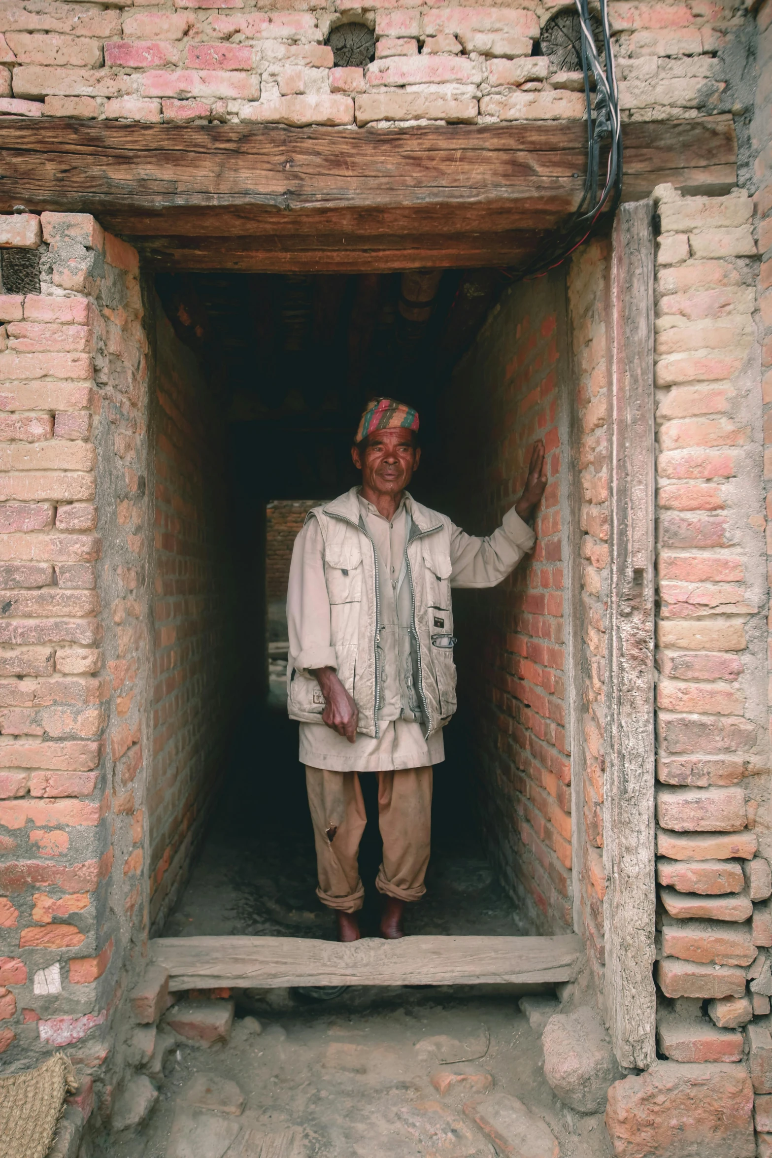 a man standing in a doorway of a brick building, inside a tomb, award winning documentary, villages, portait image