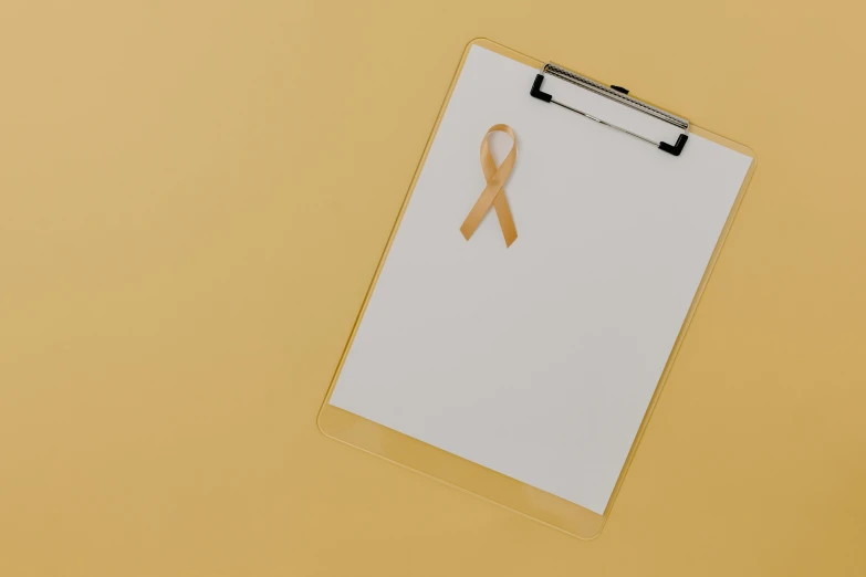 a clipboard with a gold ribbon on it, by Emma Andijewska, pexels contest winner, visual art, albino, the cure for cancer, light tan, thumbnail