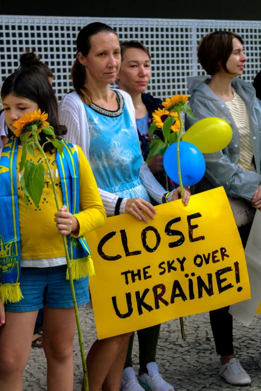 a group of people standing next to each other holding signs, by Echo Chernik, ukrainian flag on the left side, skies, slide show, flowers