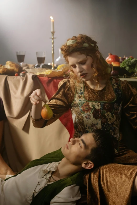 a man sitting on a couch next to a woman, inspired by Michelangelo Merisi da Caravaggio, unsplash, renaissance, eating rotting fruit, scene from live action movie, wearing medieval clothes, sophia lillis