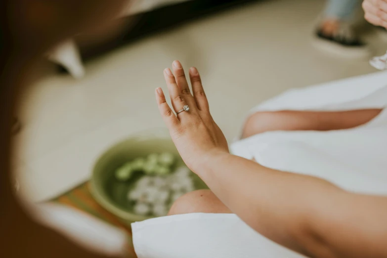 a close up of a person holding a wedding ring, by Emma Andijewska, trending on unsplash, spa, sitting cross-legged, green robe, skincare