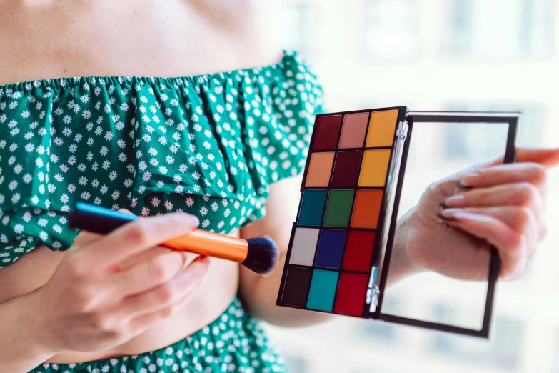 a close up of a person holding a brush and a mirror, a colorized photo, by Julia Pishtar, trending on pexels, pop art, a rubik's cube, with professional makeup, colorful outfit, teal orange color palette 8k