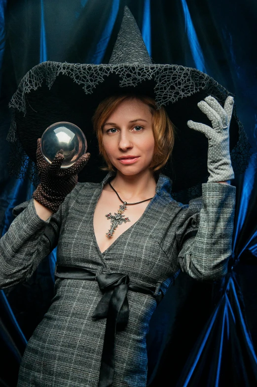 a woman in a witch costume holding a crystal ball, dasha taran, archwizzard in a hat, taken in the early 2020s, unusually attractive