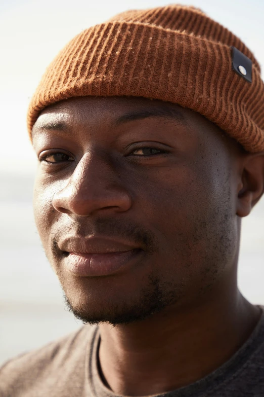 a close up of a person wearing a hat, by Charles Ellison, wearing a beanie, david uzochukwu, muted brown, smug grin