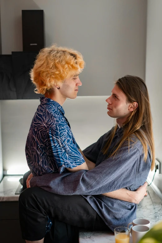 a man sitting next to a woman in a kitchen, an album cover, by Jessie Alexandra Dick, two men hugging, nonbinary model, profile image, sitting on a couch