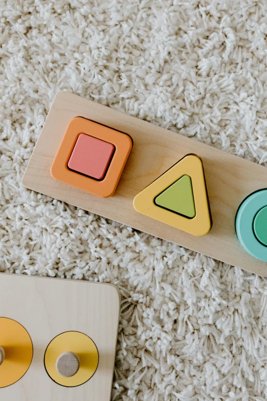 a wooden toy sitting on top of a white carpet, a jigsaw puzzle, inspired by Frederick Hammersley, trending on pexels, snacks, flat pastel colors, rounded corners, triangle