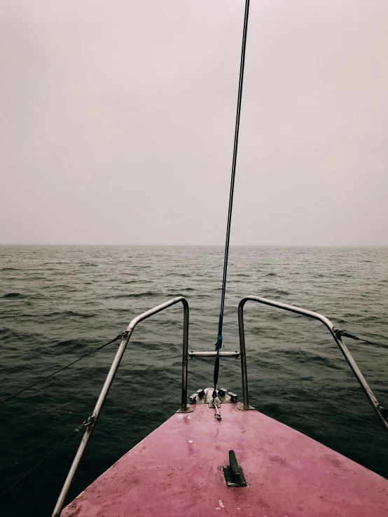 a view of the ocean from the bow of a boat, by Christen Dalsgaard, unsplash, faded pink, while it's raining, low quality photo, standing on the mast