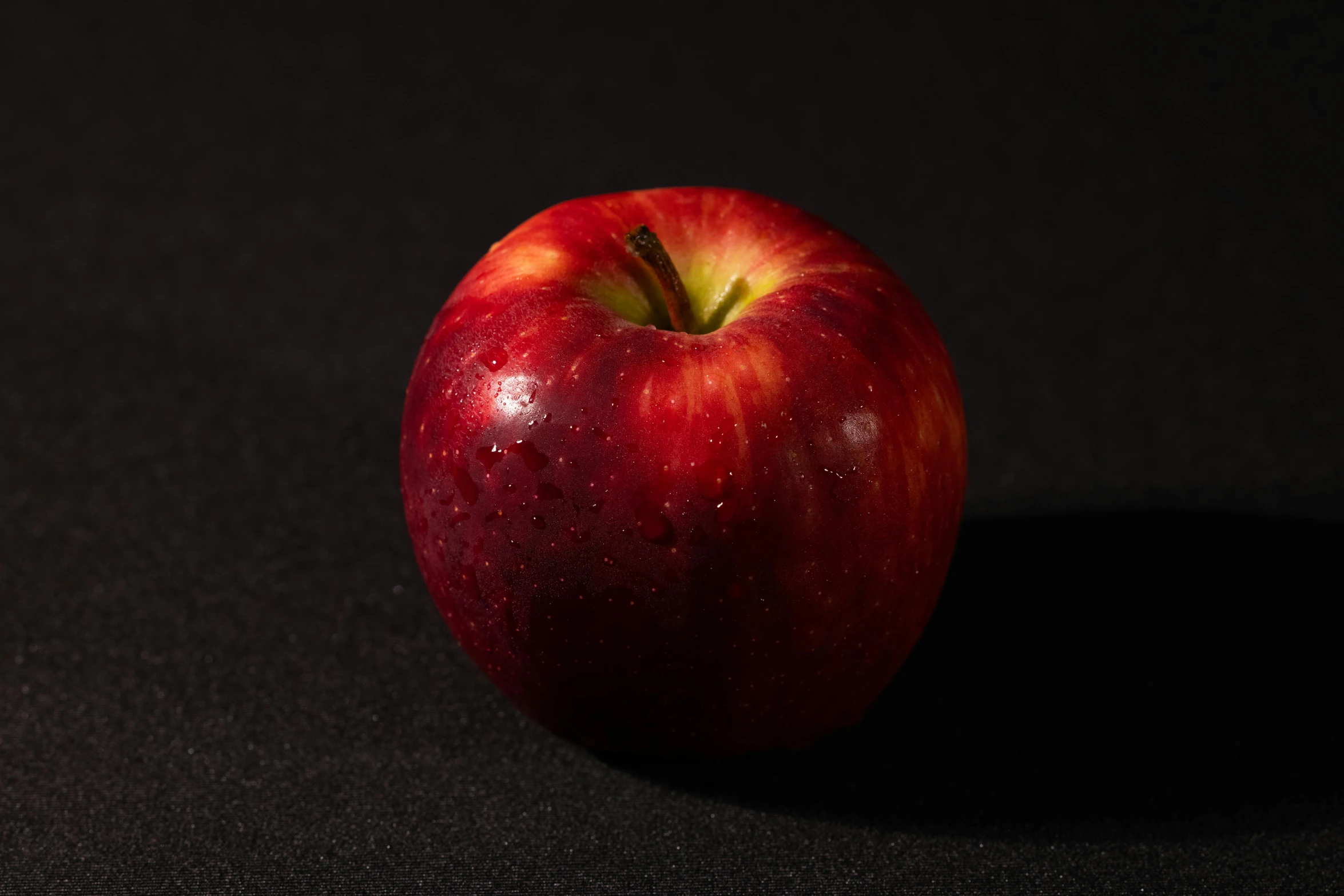 a red apple sitting on top of a black surface, detailed product image, medium angle, frontal shot, strathmore 2 0 0