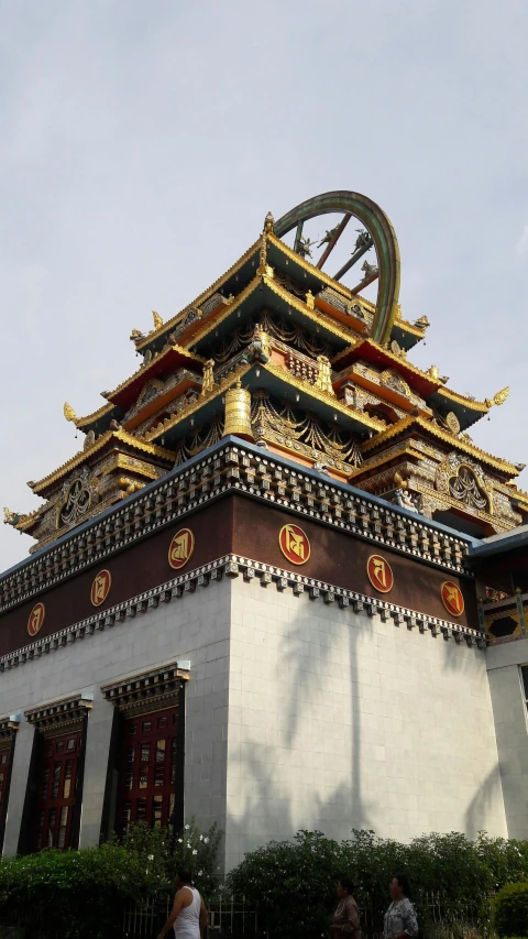 a building with a large wheel on top of it, cloisonnism, in a temple, golden detailing, grey, exterior