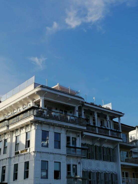 a large white building sitting on the side of a road, unsplash, quito school, roof garden, low quality photo, seaside victorian building, balcony