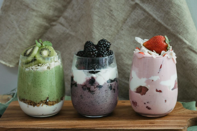 three desserts sitting on top of a wooden tray, by Emma Andijewska, trending on unsplash, inside a glass jar, yogurt, pink white and green, melbourne