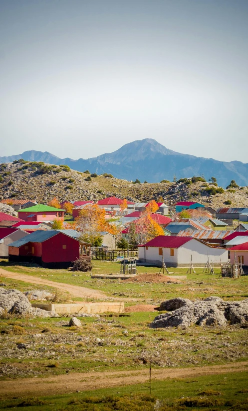 a small town with a mountain in the background, striking colour, orange roof, located in hajibektash complex, rhys lee