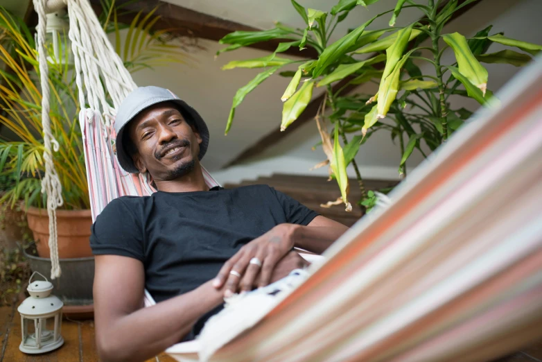 a man sitting in a hammock with a laptop, a portrait, pexels contest winner, portrait of snoop dogg, wearing a travel hat, permaculture, sitting in a lounge