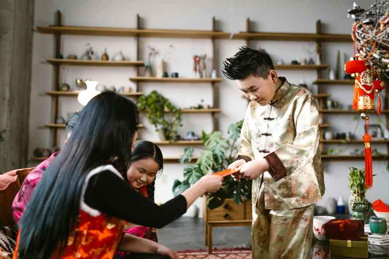 a couple of people that are sitting down, inspired by Li Di, pexels contest winner, hurufiyya, traditional chinese clothing, kids playing, presenting wares, indoor scene