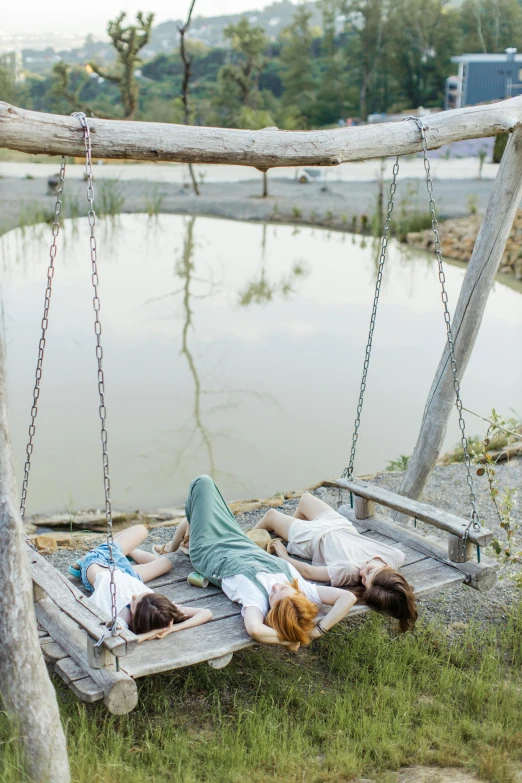 a couple of people laying on a swing, ponds, rustic setting, lagoon, highly relaxed