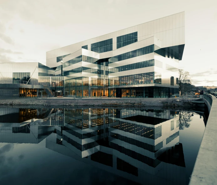 a large building sitting next to a body of water, a digital rendering, unsplash, brutalism, espoo, lots of reflective surfaces, uhq, reykjavik junior college