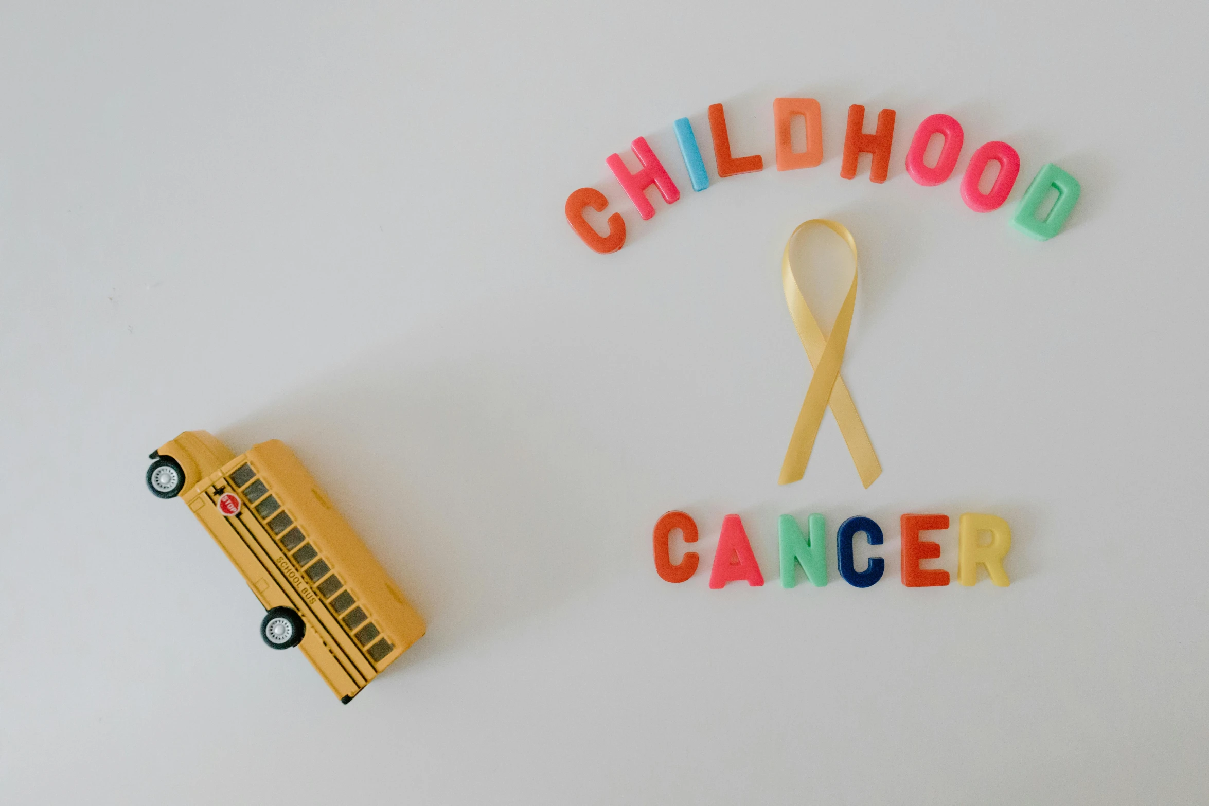 a school bus next to a sign that says childhood cancer, pexels contest winner, profile image, ribbon, cheerios, 90s photo