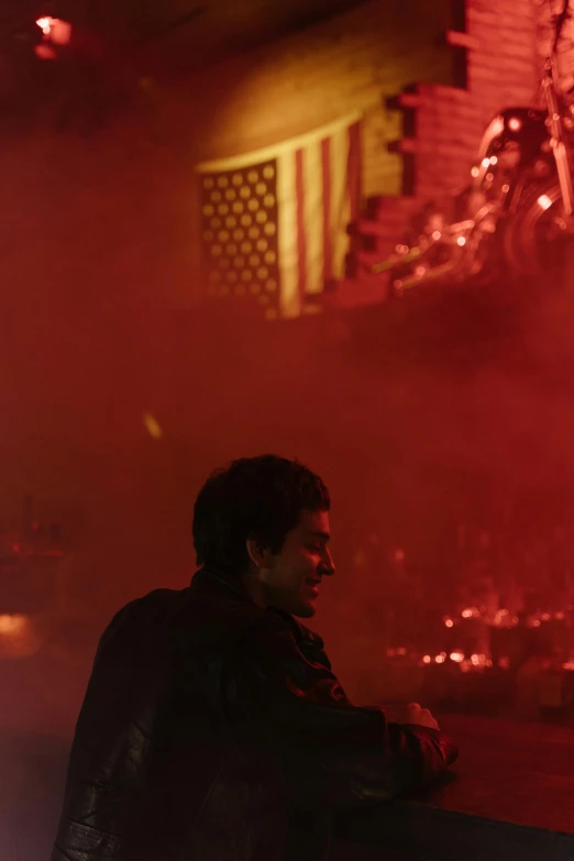 a man sitting on a bench in front of a fire, an album cover, inspired by roger deakins, unsplash, raised a bloody american flag, at a rave, al pacino, performing on stage