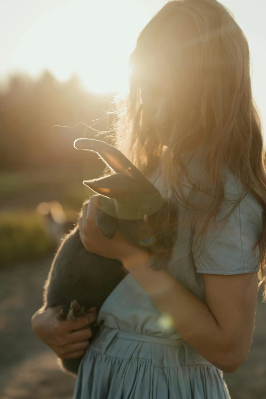 a little girl holding a rabbit in her arms, by Jan Tengnagel, unsplash, golden hour cinematic, girl and a goat, black, multiple stories