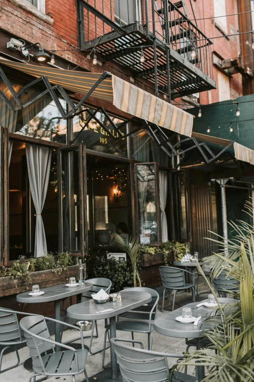 the outside of a restaurant with tables and chairs, by Zack Stella, lush brooklyn urban landscaping, julia sarda, a cozy, glamorous setting