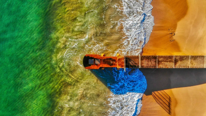 a boat sitting on top of a sandy beach next to the ocean, pexels contest winner, art photography, color aerial photo drone, blue and orange, near a jetty, splash of color