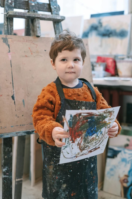 a little boy that is standing in front of a easel, inspired by Pollock, pexels contest winner, artist wearing overalls, medium close up portrait, lachlan bailey, paper marbling