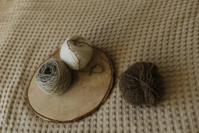 two balls of yarn sitting on top of a piece of wood, unsplash, beige, decoration, 33mm photo