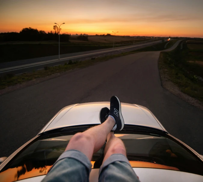 a person's feet resting on the hood of a car, by Niko Henrichon, pexels contest winner, convertible, trailing off into the horizon, end of day, head straight down