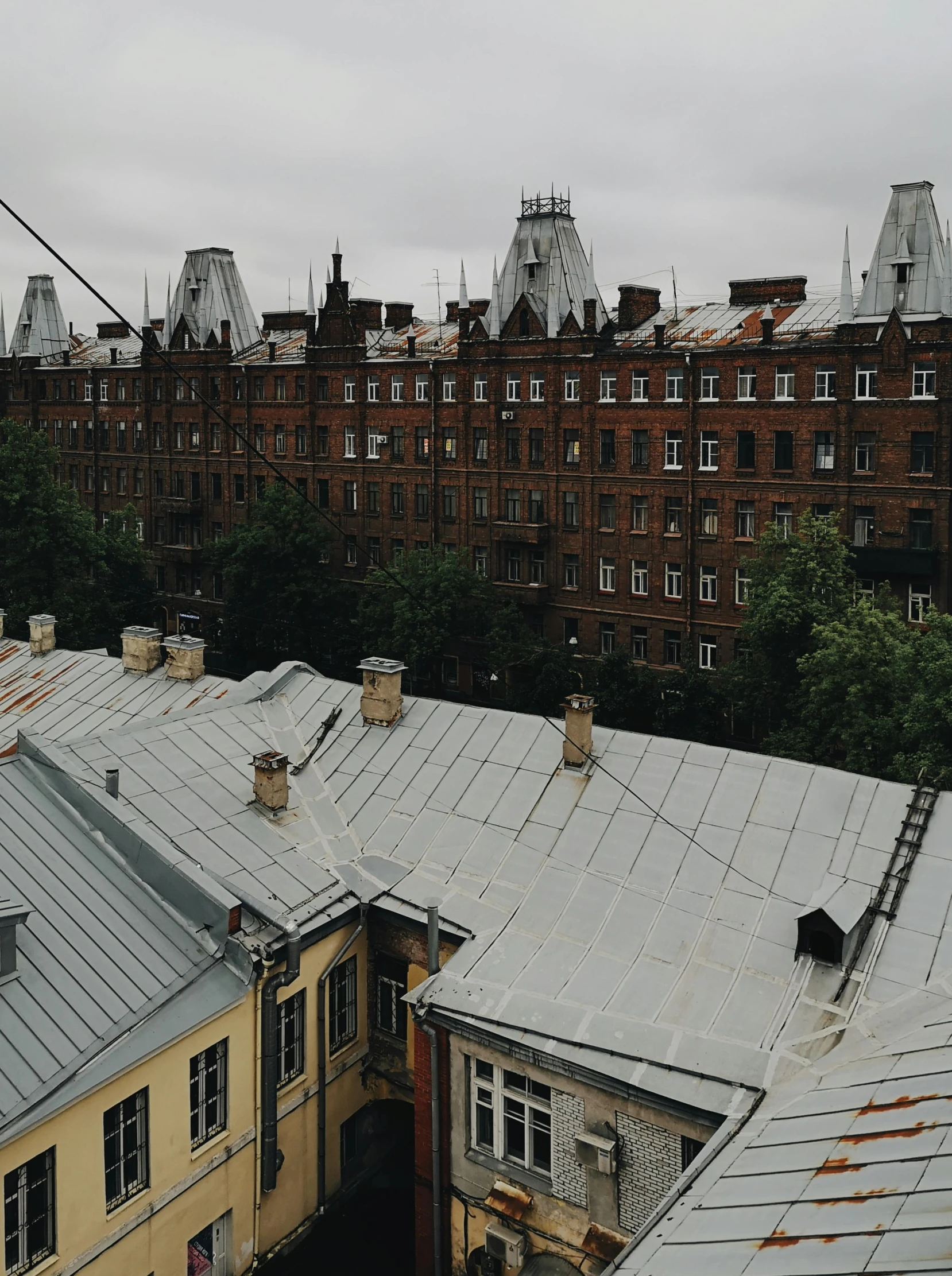 a couple of buildings that are next to each other, an album cover, inspired by Vasily Surikov, pexels contest winner, black roof, view, low quality photo, just after rain