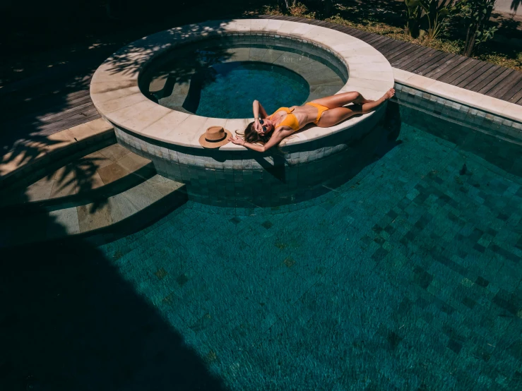 a woman laying on the edge of a swimming pool, inspired by Elsa Bleda, pexels contest winner, tonal colors outdoor, whirlpool, bali, thumbnail