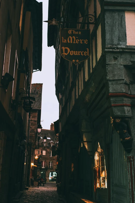 a narrow cobblestone street lined with tall buildings, inspired by Gaston Bussière, pexels contest winner, art nouveau, old signs, gryffindor, french village exterior, captured in low light