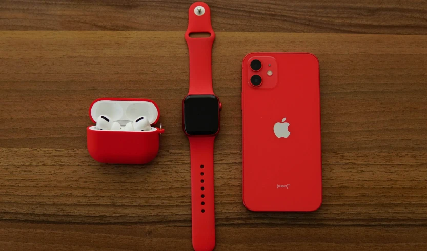 a red apple watch sitting on top of a wooden table, pexels, airpods, 🦩🪐🐞👩🏻🦳, phone photo, red and black robotic parts